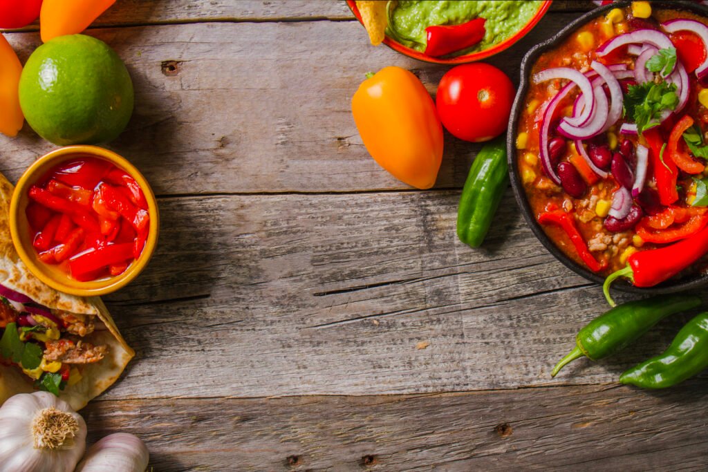 Μεξικάνικο πιάτο με καυτερές πιπεριές, φασόλια και πολύχρωμα λαχανικά σε ξύλινο τραπέζι