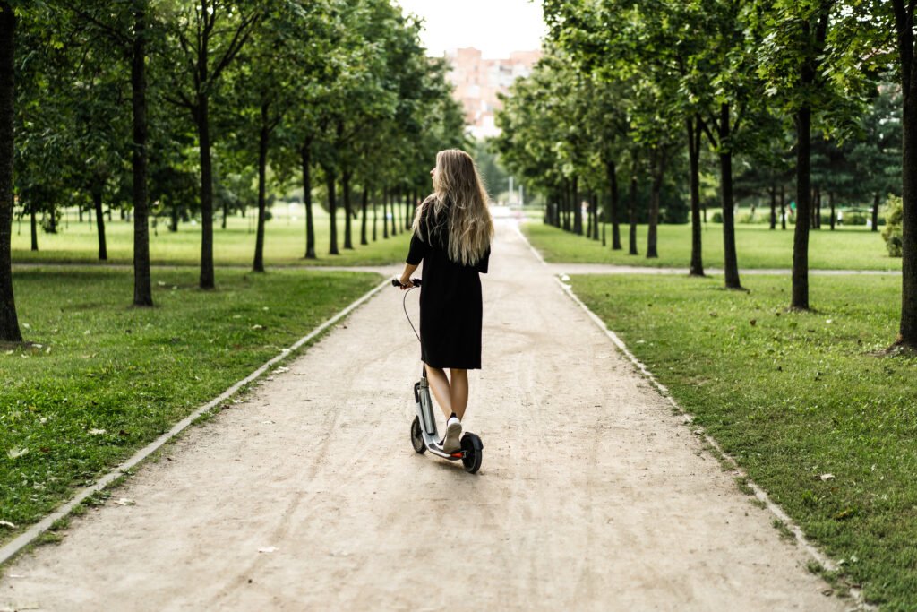 Νεαρή γυναίκα κινείται με ηλεκτρικό πατίνι σε πάρκο – οικολογική μετακίνηση στην Αθήνα